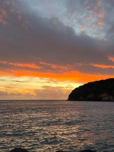 a sunset over a body of water with an island at Avó da Rosa in Ribeira Quente