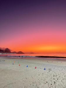 - un groupe de personnes sur une plage au coucher du soleil dans l'établissement Quartinho Copacabana-Posto 5, à Rio de Janeiro