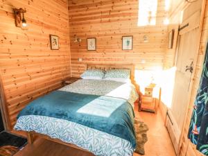 1 dormitorio con 1 cama en una cabaña de madera en Kingfisher en Rugby