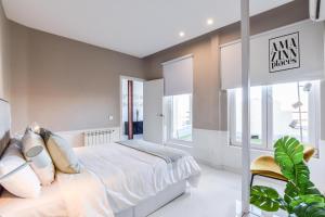 1 dormitorio con 1 cama blanca grande y ventanas en AP Embajadores IX en Madrid