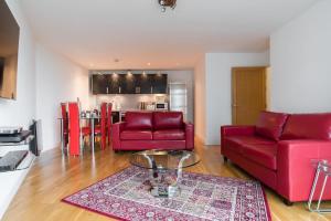 a living room with two red chairs and a table at Cardiff City Centre Apartment in Cardiff +22 photos
