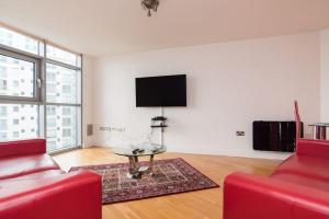 sala de estar con 2 sillas rojas y TV de pantalla plana en Cardiff City Centre Apartment, en Cardiff