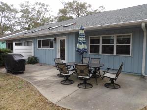 a patio with a table and chairs and an umbrella at Bike & Beach Bungalow at Oyster Bay-Sunset Beach in Sunset Beach