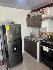 uma cozinha com um frigorífico preto e um fogão em Cabaña confortable y familiar em Coveñas