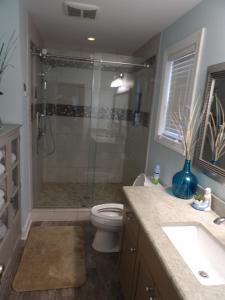 a bathroom with a shower and a toilet and a sink at Bike & Beach Bungalow at Oyster Bay-Sunset Beach in Sunset Beach +25 photos