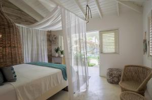 a bedroom with a canopy bed and a chair at Mahona Boutique Hotel in Las Terrenas +42 photos