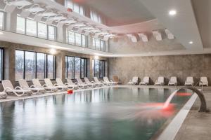 a swimming pool with white chairs and a fountain at Wellness & SPA Resort Dziwnów Apartments with Parking by Renters Prestige in Dziwnów