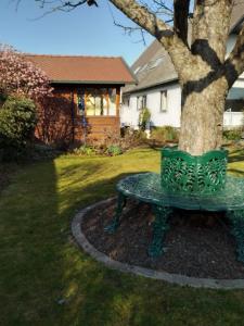 a green bench next to a tree in a yard at Komfortable Ferienwohnung in Unterbrunnenreuth in Ingolstadt