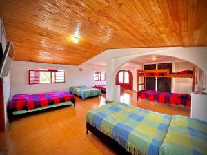 Habitación con 3 camas y techo de madera. en Hospedaje Finca Bella Vista, en Santa Rosa de Cabal