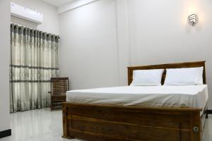 a bedroom with a bed with white sheets and pillows at Thisha Hotel & Restaurant in Jaffna +66 photos