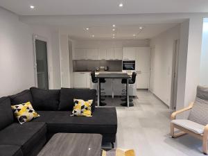 a living room with a black couch and a table at Appartement brest st-marc 6-8personne 2min centre in Brest