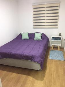 Bett mit lila Daunendecke in einem Zimmer in der Unterkunft Casona Litril in Dichato