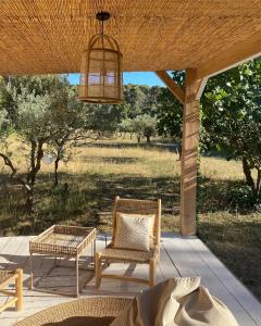 een patio met stoelen, een tafel en een kroonluchter bij Mas de Rique in Saint-Étienne-du-Grès