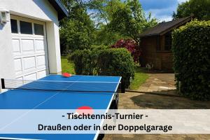 a blue ping pong table in front of a garage at Komplettes Ferienhaus für bis zu 15 Personen mit großem Garten, Pool, Dart, Sauna-, Grill- und Fitnessbereich - Ideal für Familien in Eslohe