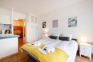 Cet appartement comprend une chambre avec un grand lit blanc et une cuisine. dans l'établissement Studio Spoerry YourHostHelper, à Grimaud