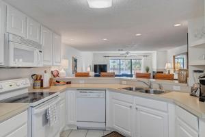 a kitchen with white cabinets and a sink at Shore Line Views in Jacksonville Beach