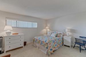 a white bedroom with a bed and a blue chair at Shore Line Views in Jacksonville Beach