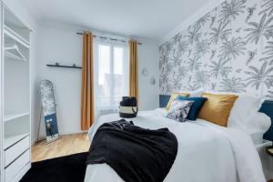 a bedroom with a large white bed with a tropical wallpaper at En route la Famille, 8 personnes - Métro 7 in La Courneuve