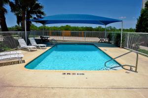 a swimming pool with a blue umbrella and chairs at Motel 6-San Antonio, TX - Downtown - Alamo Dome in San Antonio