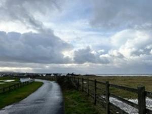 uma estrada com uma cerca ao lado de um campo em Beach House em Donegal