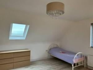 um quarto com uma cama, uma janela e um lustre em Beach House em Donegal