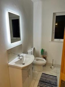 La salle de bains blanche est pourvue d'un lavabo et de toilettes. dans l'établissement Beach House, à Donegal