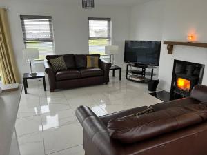 uma sala de estar com sofás de couro e uma lareira em Beach House em Donegal