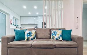 Central Tiled Apartment في أفيرو: أريكة بنية مع وسائد زرقاء في غرفة المعيشة