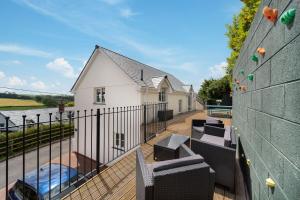 a balcony with chairs and a swimming pool on a house at Goodleigh Cottage in Goodleigh