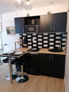 eine Küche mit schwarzen Schränken, einem Tisch und einer Mikrowelle in der Unterkunft Studio à deux pas de la mer in Berck-sur-Mer