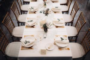 un tavolo per un matrimonio con piatti e fiori bianchi di Pensiunea Retezat a Râu de Mori