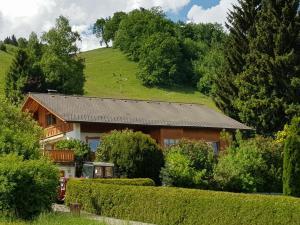 a house with a green hill in the background at Ferienwohnung Schloßberg 1 in Peiting