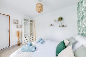 ein weißes Schlafzimmer mit einem weißen Bett und blauen Kissen in der Unterkunft Le Grand Danton - 4 personnes - Parking, Métro 7 in La Courneuve