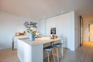 a kitchen with a counter and two stools in a room at The Loft - Full Sea View - use of hotels Sauna and Pool in Cadzand