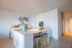 cocina con encimera y 2 taburetes en una habitación en The Loft - Full Sea View - use of hotels Sauna and Pool, en Cadzand