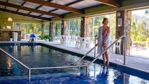 a woman standing on a hand rail next to a swimming pool at Villa Bella Hotel & SPA Gramado in Gramado