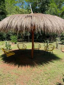 einen Strohschirm mit zwei Stühlen darunter in der Unterkunft Posada Turística Las Orquídeas in Cambyretá