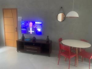 sala de estar con mesa, TV, mesa y sillas en Apto 2o andar novo 2 dorm - próximo ao centro, en Poços de Caldas