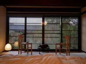 um quarto com 2 cadeiras, uma cama e uma janela grande em Satoyama villa DEN - Vacation STAY 14150 em Matsumoto