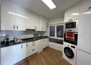 a kitchen with white cabinets and a washing machine at Tía Ana in Gijón