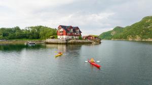 two people in kayaks in the water in front of a house at Brygga på Dønna 