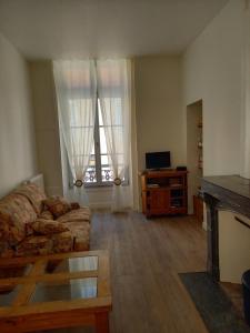 a living room with a couch and a table and window at Les Meublés du Colombier in Lons-le-Saunier