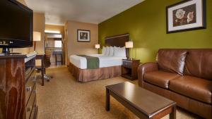 SureStay Hotel by Best Western Floresville في Floresville: غرفه فندقيه بسرير واريكه