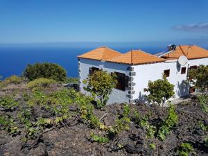 uma casa numa colina com o oceano ao fundo em House the Viñas 2 With views of the sea, the mountains and the volcanoes em Fuencaliente de la Palma