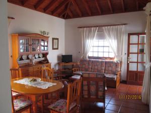 ein Wohnzimmer mit einem Tisch, Stühlen und einem Fenster in der Unterkunft House the Viñas 2 With views of the sea, the mountains and the volcanoes in Fuencaliente de la Palma