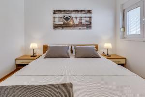 a bedroom with a large white bed with two lamps at Apartments Juraj in Petrcane