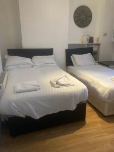 Dos camas en una habitación con un reloj en la pared. en Lovely Studio Flat @ 10C Nearby Sea Front, en Ryde