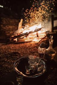 a table with glasses and a bottle and a fire at Pensiunea Retezat in Rîu de Mori