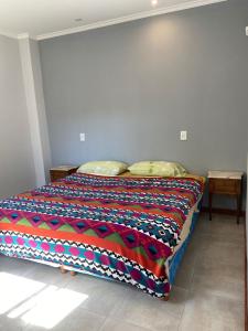 Una cama con una manta de colores en una habitación en Casa espaciosa en Ramallo cerca del Río en Ramallo