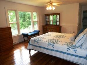Schlafzimmer mit einem Bett, einer Kommode und Fenstern in der Unterkunft Light Of The Valley River House in Woodstock